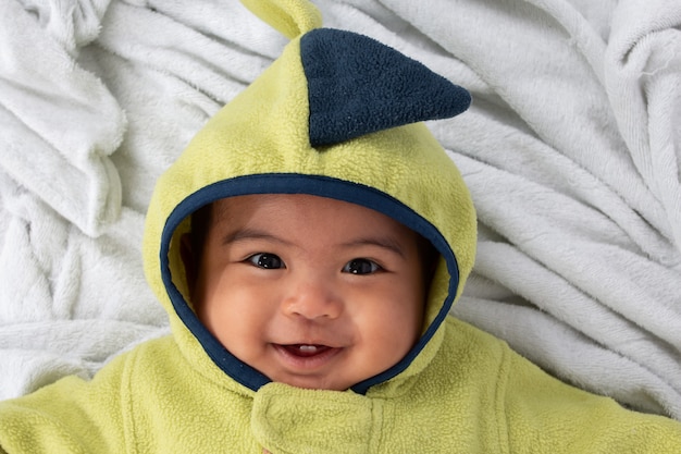 Piccolo neonato felice che si trova sulla coperta e sul sorriso molli