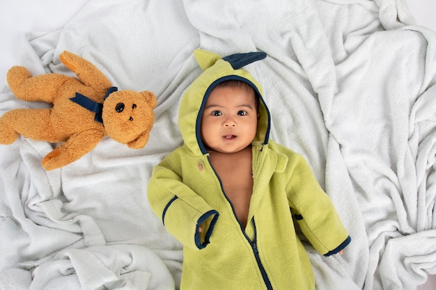 Foto piccolo neonato felice che si trova sulla coperta e sul sorriso molli