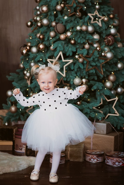 happy little blonde girl by the christmas tree