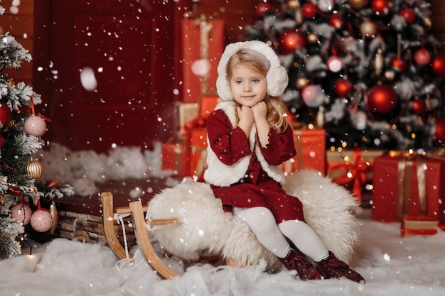 Happy little blonde girl in a fur vest and headphones, waiting for Christmas and New year in the