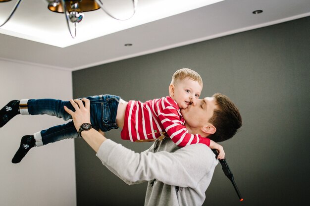 Happy little boy and dad in Santa Claus sweaters play and celebrate Christmas