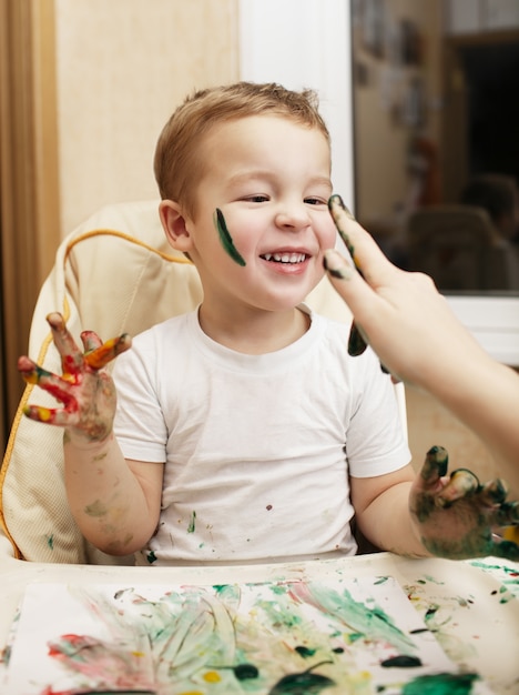 Happy little boy doing finger painting