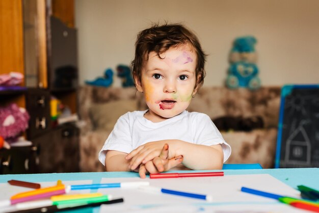 Foto un ragazzino felice disegna con marcatori colorati su un pezzo di carta