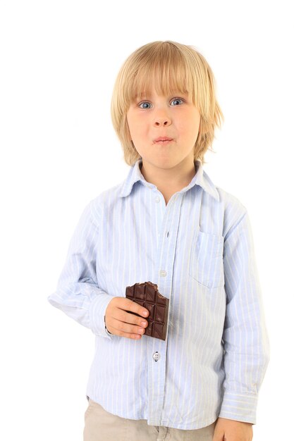 Счастливый маленький мальчик ест шоколад, изолированные на белом
