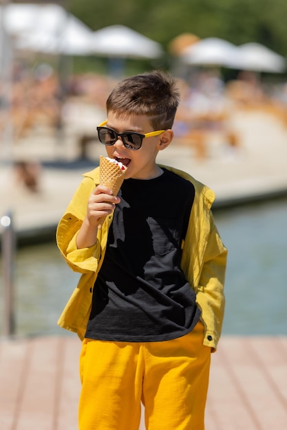 Happy little boy eats ice cream in a waffle cone in summer on a walk