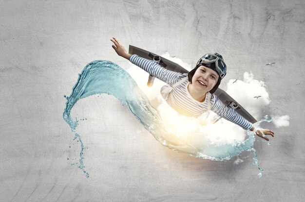 Photo happy little boy flying while wearing helmet. mixed media