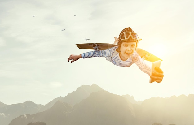 Happy little boy flying while wearing helmet. Mixed media