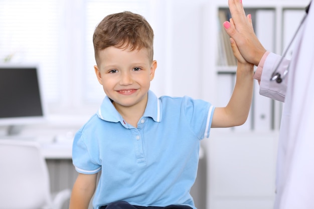 Happy little boy giving high five after health exam at doctor's office