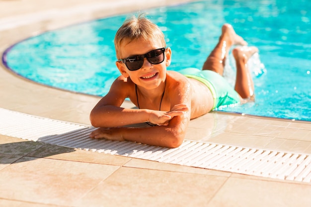 Фото Счастливый маленький мальчик развлекается в бассейне на курорте