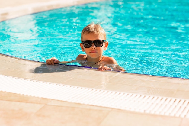 Foto ragazzino felice che si diverte in piscina presso il resort