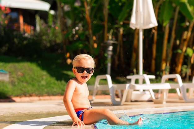 Foto ragazzino felice che si diverte in piscina presso il resort