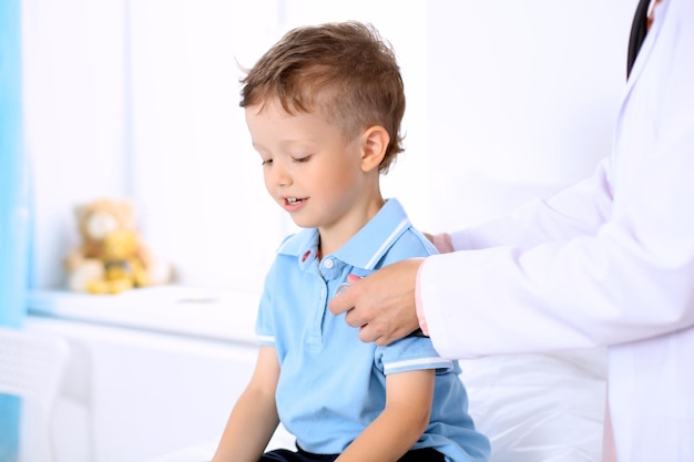 Happy little boy having fun while is being examine by doctor by stethoscope Health care insurance and help concept