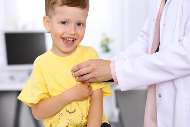 Happy little boy having fun while is being examine by doctor by stethoscope Health care insurance and help concept