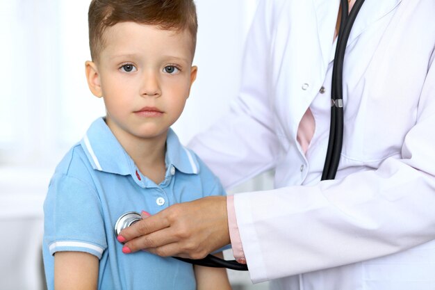 Happy little boy having fun while is being examine by doctor with stethoscope