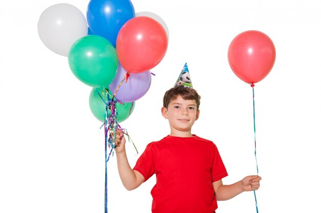 Happy little boy holding bunch of balloons