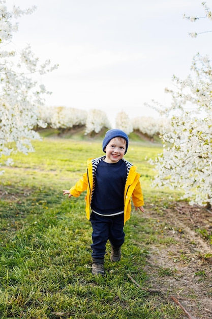 Счастливый маленький мальчик бежит по цветущему саду Счастливое детство