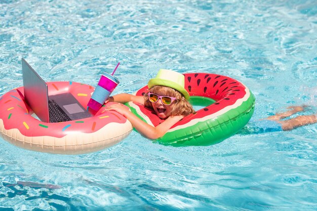 Happy little boy learning online computer laptop child relax and rest on colorful inflatable ring us