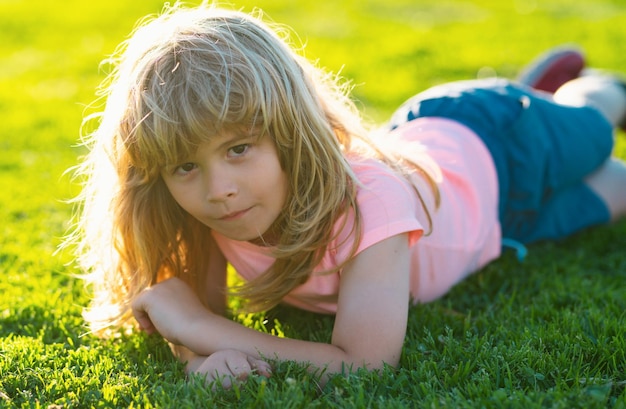 Happy little boy lying on the grass at the summer park portrait of a smiling child lying on green