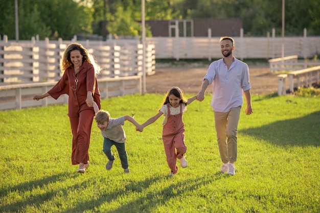 Happy little boy running while holding by hands of his mother and sister