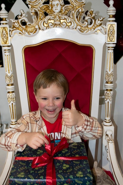 Photo happy little boy in santa's hat sitting in a room decorated for christmas