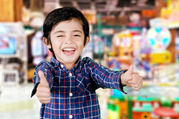 Happy little boy showing thumbs up in game center