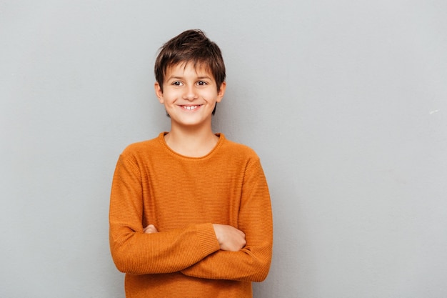 Happy little boy standing with arms crossed