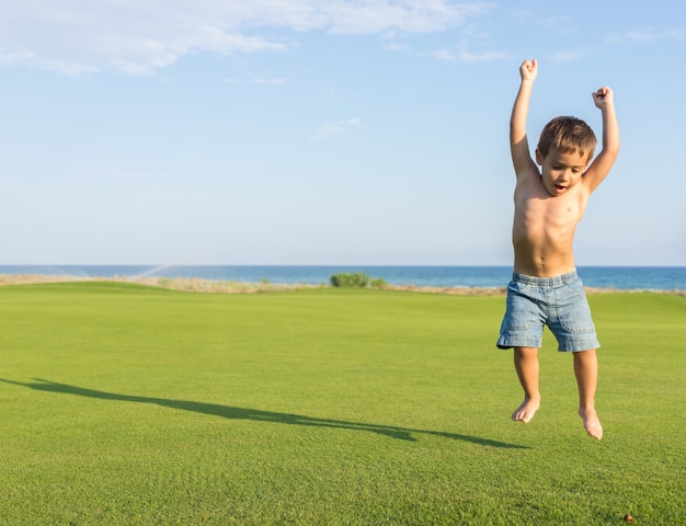 Happy little boy on summer gulf grass terrain having fun and happy time