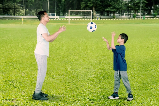 幸せな小さな男の子が父親にボールを投げる