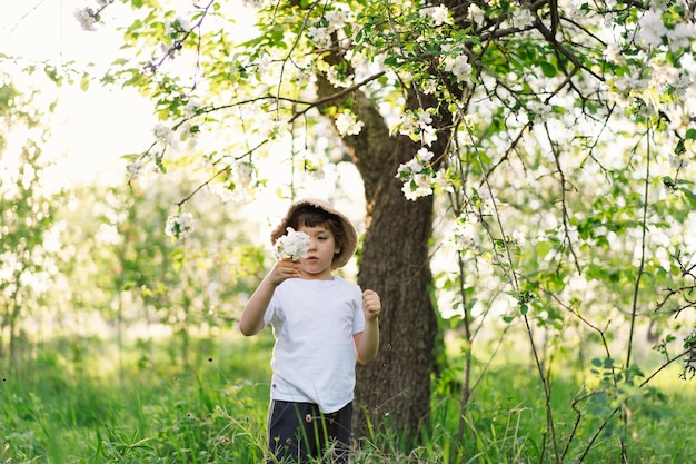 Happy little boy walking in spring garden child playing with\
branch of an apple treeand having fun kid exploring nature baby\
having fun spring activity for inquisitive children