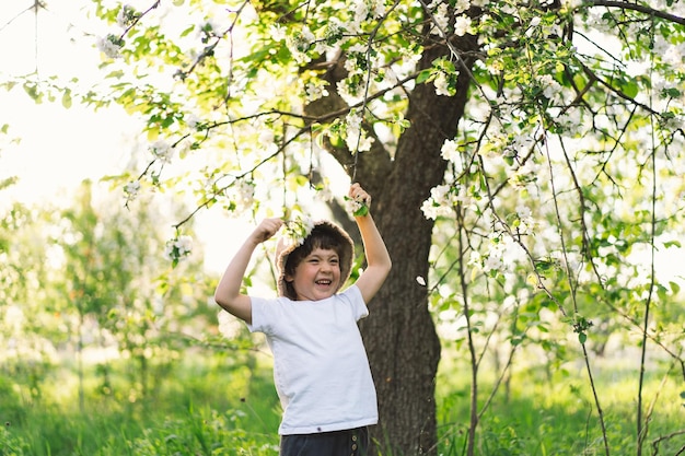 Happy little boy walking in spring garden child playing with\
branch of an apple treeand having fun kid exploring nature baby\
having fun spring activity for inquisitive children