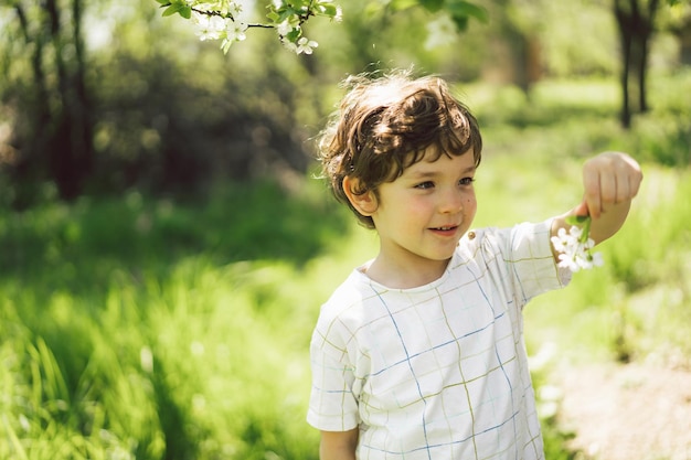 Happy little boy walking in spring garden Child playing with branch of an cherry tree and having fun Kid exploring nature Baby having fun Spring activity for inquisitive children