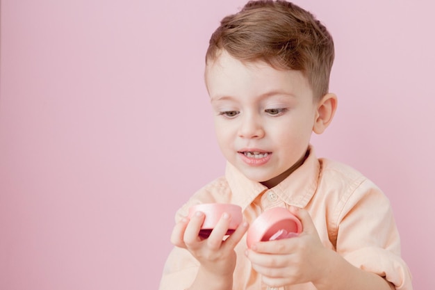 Happy little boy with a gift Photo isolated on pink background Smiling boy holds present box Concept of holidays and birthday