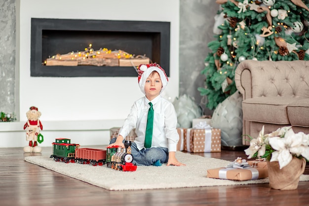 Happy little boy with a gift toy train under the Christmas tree on a New Years morning