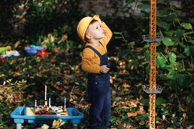 Happy little boy with remote control from radiocontrolled toy construction crane in the park