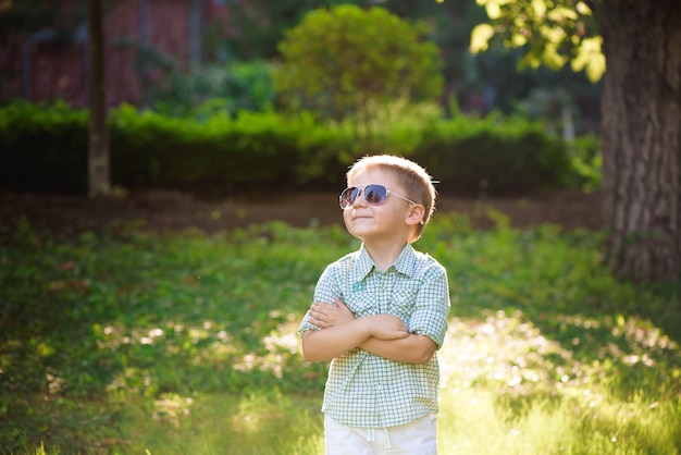 Happy little boy with sunglasses in the garden.