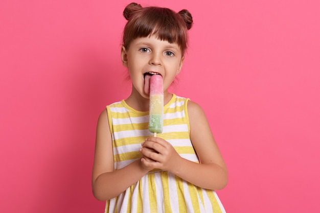 Happy little charming female kid licking water ice