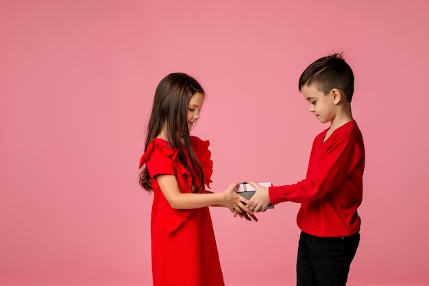 Happy little child boy gives smiling girl a gift box