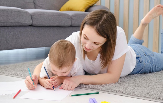 Happy little child boy hand drawing pictures with mom