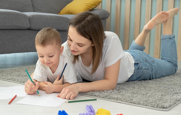 Happy little child boy hand drawing pictures with mom