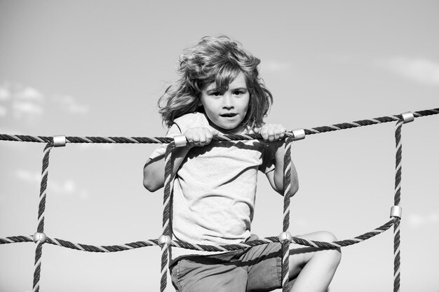 Photo happy little child boy on the web in outdoor playground kid enjoying playing summer activities kids