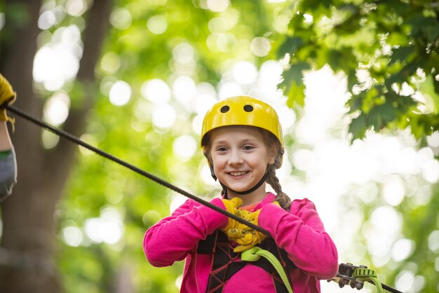 ロープの遊び場に登る幸せな小さな子供屋外のかわいい子供が安全装置を登る...