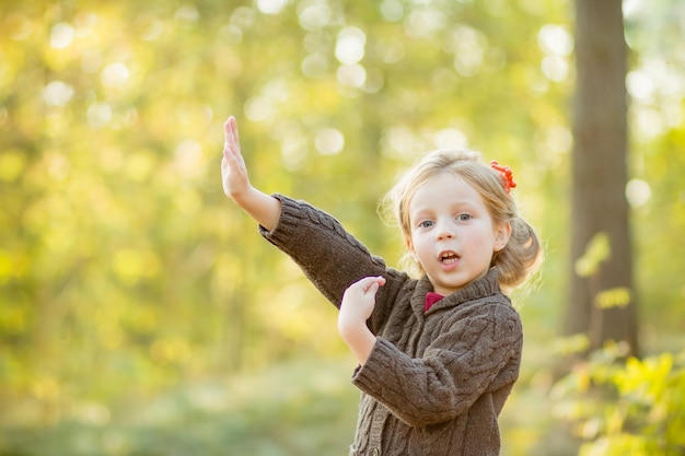 Happy little child girl 45 year old playing outdoor Girl is wearing warm jacket she is dancing jumpingspending a weekend in autumn park Autumnal moodChildhood Autumn season