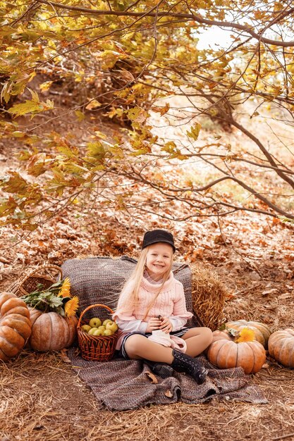 かわいいハリネズミと幸せな小さな子の女の子秋の自然の中でペットとカボチャとわらが温かい飲み物のカップを保持している子供の肖像画