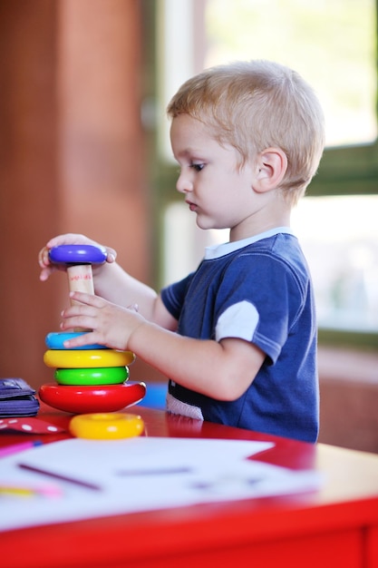 счастливый маленький ребенок играет в игры и веселится, образовательные уроки на красочной детской площадке в саду в помещении
