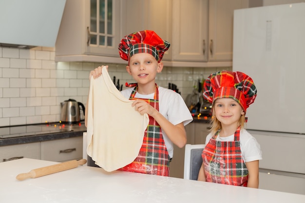 Photo happy little children cooks christmas cookies at home in kitchen in a chef costume