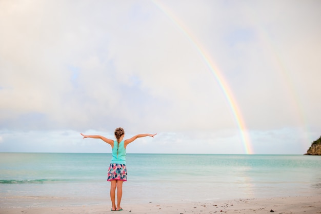 Happy little girl backgound the beautiful rainbow over the sea