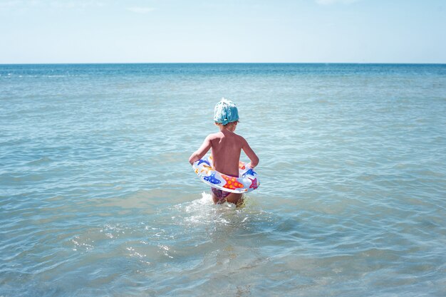 La bambina felice bagna in acqua blu su un cerchio gonfiabile