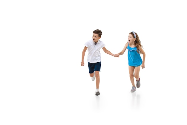 Happy little girl and boy running on white background