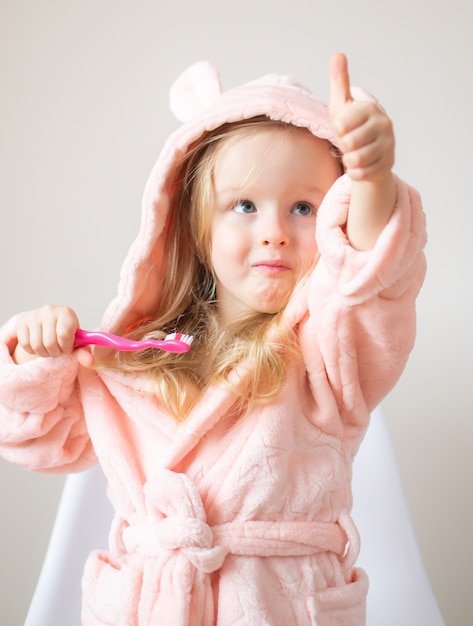 Счастливая маленькая девочка чистит зубы, розовая зубная щетка, гигиена полости рта, утренняя ночь