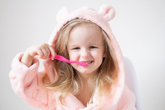 Photo happy little girl brushing her teeth, pink toothbrush, dental hygiene, morning night healthy concept lifestyle